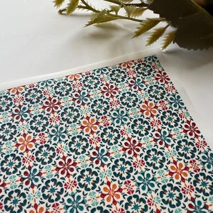 Może przedstawiać: Wzorzysty papier z powtarzającym się kwiatowym wzorem w odcieniach czerwieni, turkusu i pomarańczy na kremowym tle. Szczegółowy kwiatowy wzór tworzy atrakcyjną wizualnie powierzchnię. Papier ten jest prawdopodobnie używany do rękodzieła lub artykułów papierniczych.