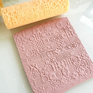 Pu&ograve; includere: Un mattarello a motivi giallo chiaro e un tappetino rosa strutturato. Il mattarello presenta un motivo ripetuto di quadrati, fiori e forme geometriche. Il tappetino rosa presenta un motivo ripetuto simile di quadrati e motivi floreali.