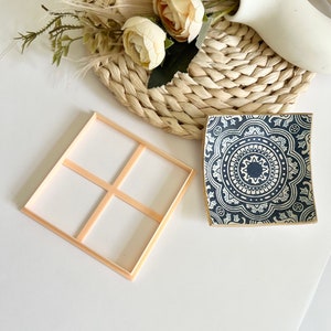 May include: A wooden tray with four square compartments and a blue and white ceramic dish with a mandala design.