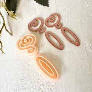 Puede incluir: Dos juegos de pinzas para el pelo en diferentes colores. Un juego es de oro rosa y el otro es de melocotón. Las pinzas de oro rosa tienen forma de espiral y las pinzas de melocotón tienen forma ovalada.