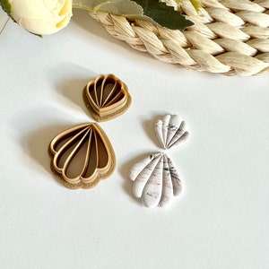 Può includere: Due tagliabiscotti in plastica marrone a forma di conchiglia e due orecchini in pasta polimerica bianca a forma di conchiglia.