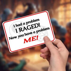 May include: A white rectangular card with a red border is held in a hand. The card features the text "I had a problem I RAGED! Now you have a problem ME!" in black and red font. The background is blurred.