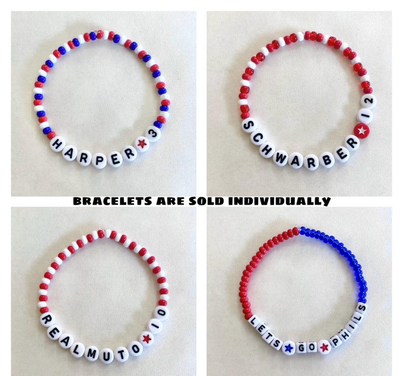 May include: Four beaded bracelets in red, white, and blue. Each bracelet features white letter beads spelling out names and phrases, with star accents. The text "BRACELETS ARE SOLD INDIVIDUALLY" is also present.