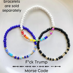 May include: Three beaded bracelets in white, blue, and black, with gold accents. The blue bracelet features rainbow-colored beads. Text on the image reads "F*ck Trump" in Morse code, with the words "bracelets are sold separately" and "Morse Code".