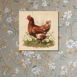 Op de afbeelding: Vierkante houten wandkunst met een bruine kip die in een veld met madeliefjes staat. Het kunstwerk heeft een rustieke, vintage stijl, met een lichtgekleurde houten achtergrond. De kip is afgebeeld met gedetailleerde veren en een rode kam.