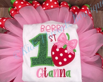 Könnte beinhalten: Ein weißes T-Shirt mit einer grünen Glitzer-Eins, einer roten Erdbeere mit weißen Punkten und einer rosa Schleife sowie dem Text BERRY 1ST GIANNA, platziert auf einem rosa Tüll-Tutu-Rock mit einem rot-weiß gepunkteten Band am Saum.