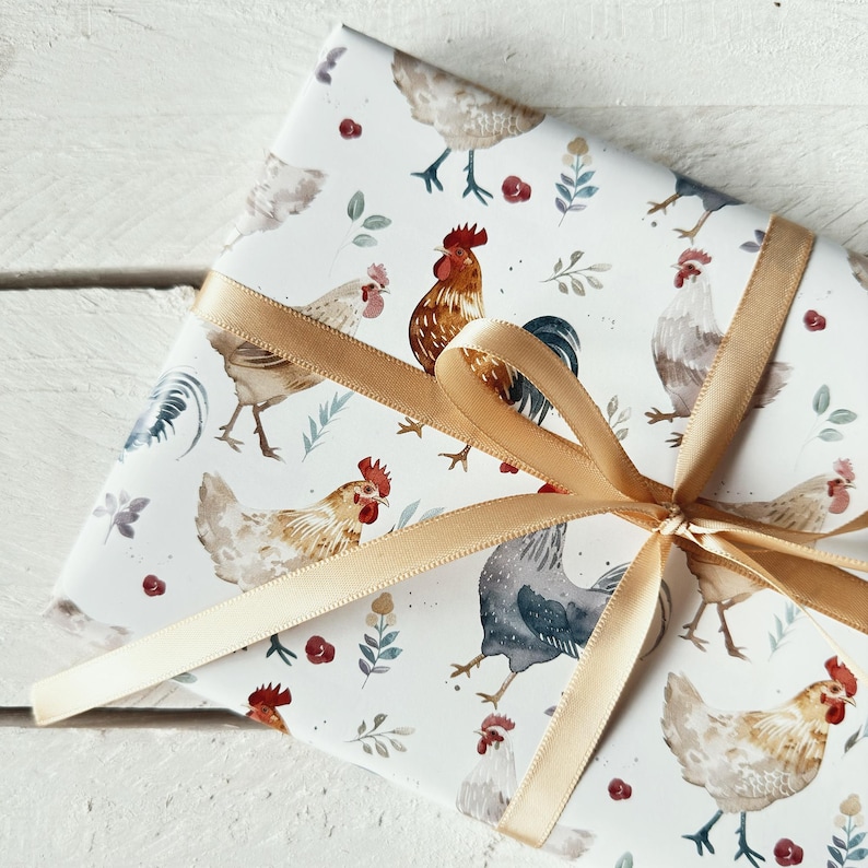 May include: White gift wrap with a repeating pattern of watercolor chickens and roosters. The paper is tied with a gold ribbon.