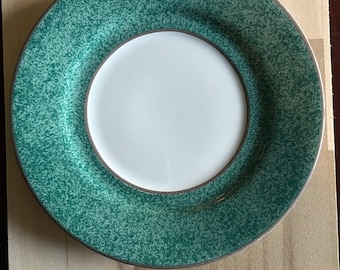 May include: A green and white ceramic saucer with a speckled green design and a brown rim.