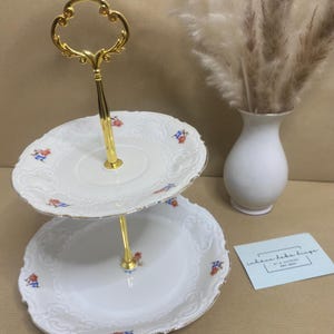 Könnte beinhalten: Eine weiße Keramik-Tasse mit schwarzem Henkel und dem Text "But First, Coffee" in handschriftlichem Stil. Die Tasse steht auf einer weißen Oberfläche. Die Tasse ist wahrscheinlich für Heißgetränke.