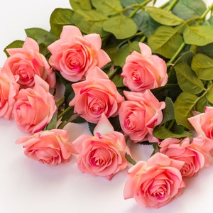 May include: A bouquet of pink roses with green leaves on a white background.