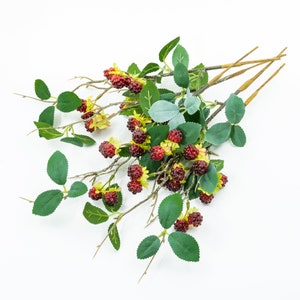 May include: A bunch of artificial blackberry stems with green leaves and red berries. The stems are brown and have a natural look.