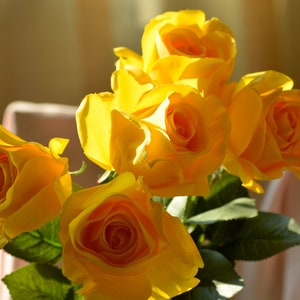 Pode incluir: Um buqu&ecirc; de rosas amarelas com folhas verdes. As rosas est&atilde;o em foco e o fundo est&aacute; desfocado.