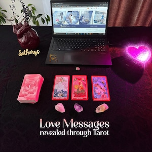 May include: A laptop displays book covers, with a stack of pink tarot cards and three face-up cards. The text "Love Messages revealed through Tarot" is at the bottom. Pink and clear crystals are scattered around the cards, with a heart-shaped vase and a glowing heart.