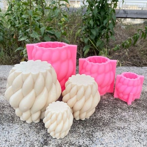 Könnte beinhalten: Vier Silikonformen zum Herstellen von Beton-Pflanzgefäßen. Die Formen sind in verschiedenen Größen und mit einem geflochtenen Design. Die Formen sind rosa und weiß.