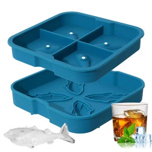 May include: Two teal silicone ice cube trays, one with square molds and the other with shark-shaped molds. A clear shark-shaped ice cube and a glass of whiskey with ice and mint are also visible.