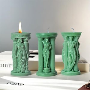 May include: Three green pillar candles, each featuring a sculpted female figure. The candles are lit and have a flame on top.