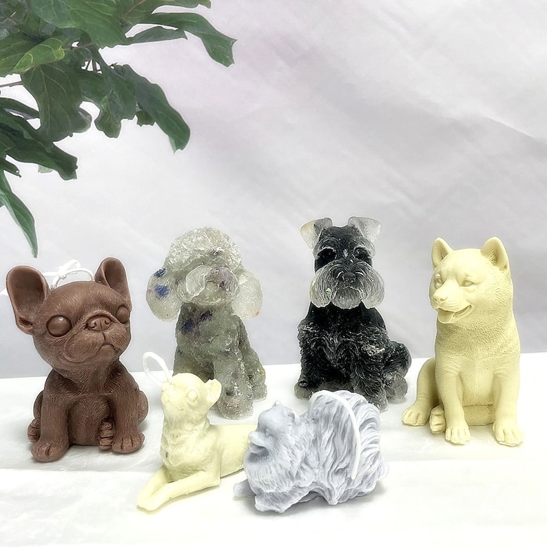 May include: Six different dog-shaped candles in various colors and poses. The candles are made of wax and have a realistic appearance. The candles are arranged on a white surface.