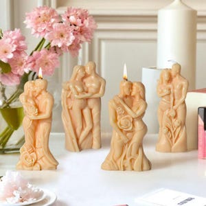 Puede incluir: Cuatro velas decorativas con forma de parejas abrazándose. Las velas son de cera beige y tienen un aspecto realista y esculpido.
