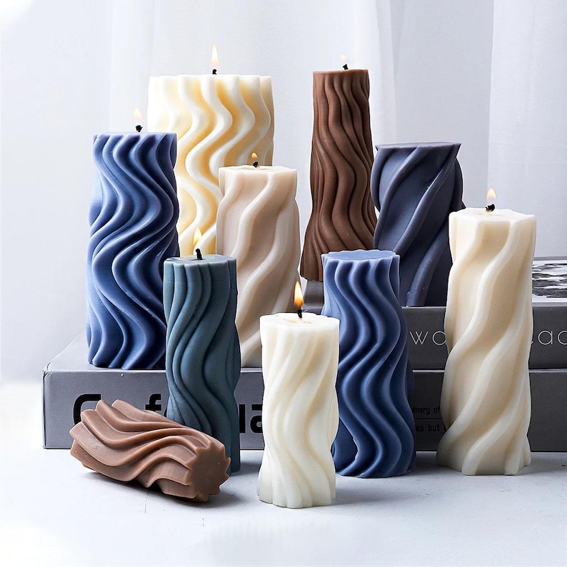 K&ouml;nnte beinhalten: Sortiment an dekorativen Kerzen in verschiedenen Farben und Designs. Die Kerzen haben alle ein wellenf&ouml;rmiges Muster und sind aus Wachs. Die Kerzen sind auf einem Tisch mit einer Holzoberfl&auml;che angeordnet.