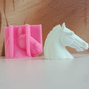 Könnte beinhalten: Eine rosa Silikonform und eine weiße Gips-Pferdekopfskulptur. Die Form ist dazu bestimmt, eine Pferdekopfskulptur zu erstellen.