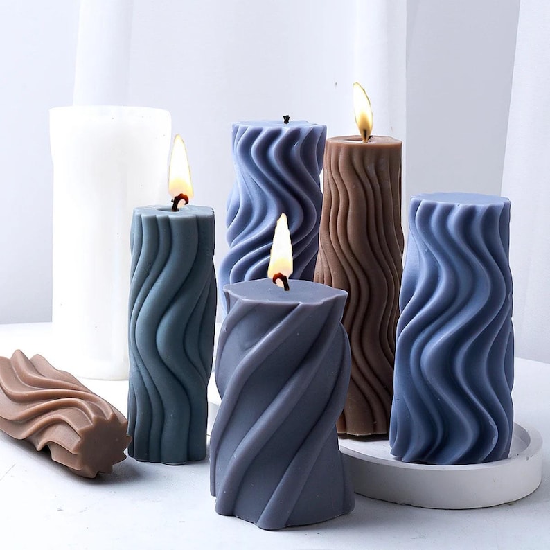 K&ouml;nnte beinhalten: F&uuml;nf dekorative Kerzen mit einem wellenf&ouml;rmigen Design. Die Kerzen sind in den Farben Braun, Blau und Grau gehalten. Die Kerzen sind angez&uuml;ndet und die Flammen sind sichtbar.