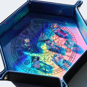 May include: A hexagonal iridescent blue dice tray with a black border and a circular design of zodiac symbols. The tray is filled with iridescent dice.
