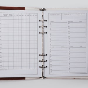 May include: A white, two-page, spiral bound notebook with a gridded section on the left page and a section for spellcasting ability, spell save DC, and spell attack bonus on the right page. The notebook is open and the pages are blank.