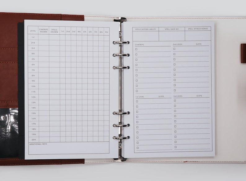 May include: A white, two-page, spiral bound notebook with a gridded section on the left page and a section for spellcasting ability, spell save DC, and spell attack bonus on the right page. The notebook is open and the pages are blank.