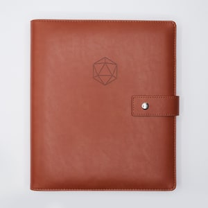 May include: A brown leather bound journal with a geometric design embossed on the front cover. The journal has a strap closure with a silver button.