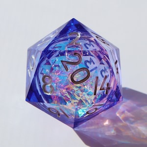 May include: A large, blue, twenty-sided die with silver numbering. The die is transparent, revealing a colourful, iridescent interior. The die is designed for tabletop role-playing games.