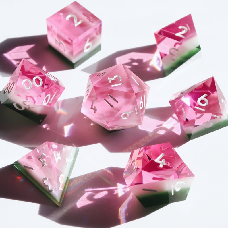 May include: Set of ten pink and green watermelon dice with white numbers. The dice are made of clear acrylic with a pink and green swirl pattern.