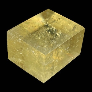 May include: A large, clear, yellow crystal with a cubic shape. The crystal is translucent and has a slightly cloudy appearance.