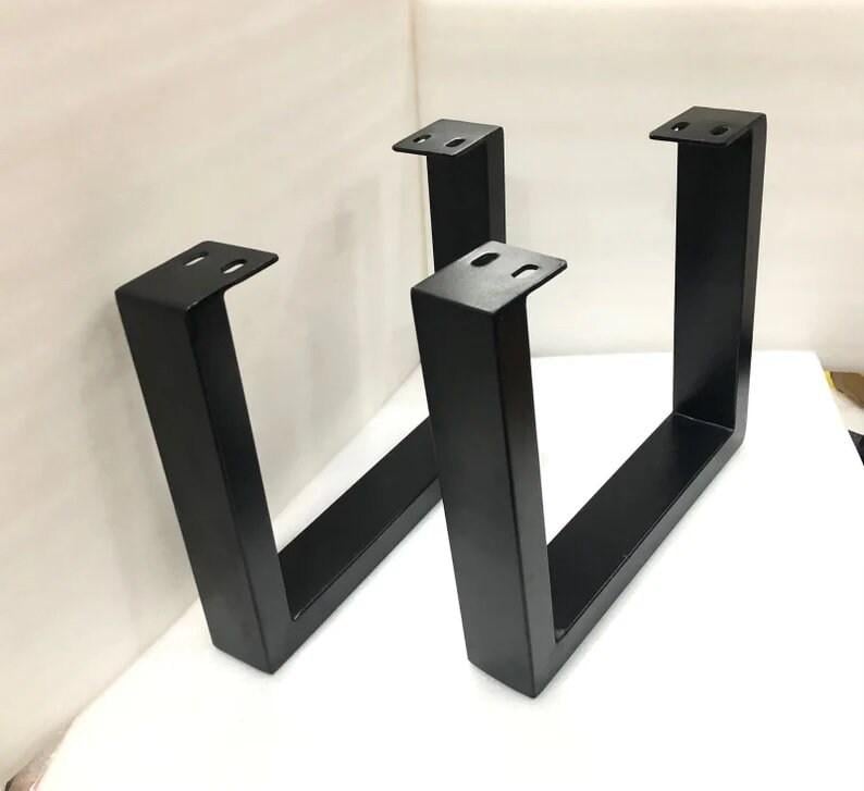 May include: Two black metal table legs in a U-shape design. Each leg has a flat top with pre-drilled holes for easy attachment. The legs are made of sturdy metal and are suitable for various furniture projects.