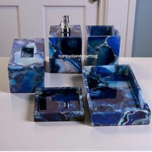 Puede incluir: Un juego de cinco accesorios de baño de piedra de ágata azul y blanca. El juego incluye un dispensador de jabón, una caja de pañuelos, un porta cepillos de dientes, una bandeja pequeña y una bandeja más grande. El texto "turquoisestonerring" es visible.