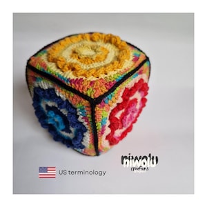 May include: A colorful, crocheted cube with a spiral design on each face. The cube features a variety of colors, including yellow, blue, red, and green, with black edging. The cube is handmade and has a unique, textured appearance.