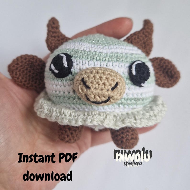 May include: A handmade crochet cow toy with a striped head in white and light green. The cow has brown horns, ears, and feet, with large black eyes and a tan snout. The text "Instant PDF download" is visible.