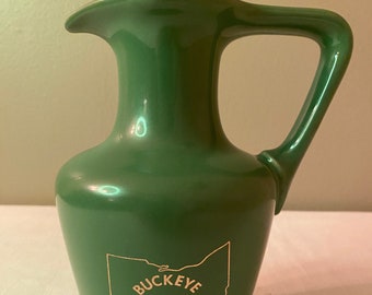 May include: Green ceramic pitcher with a gold outline of the state of Ohio and the text "Buckeye Jim Beam Bottle Club".