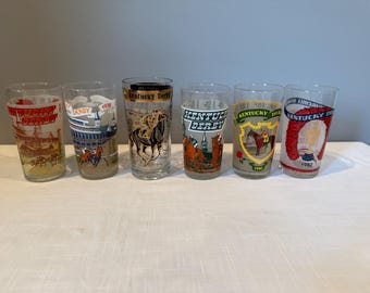 Könnte beinhalten: Sechs klare Glasbecher mit bunten Designs zum Thema Kentucky Derby. Jedes Glas zeigt ein anderes Jahr und eine Pferderenn-Szene.