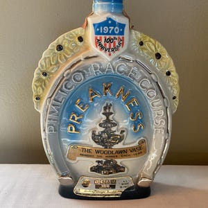 May include: A vintage ceramic bottle commemorating the 100th Anniversary of the 1970 Preakness Stakes. The bottle features a horseshoe shape with the words "Preakness" and "Pimlico Race Course". It also includes the text "The Woodlawn Vase".