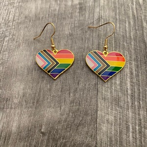 May include: A pair of gold heart-shaped earrings with a rainbow and black and brown geometric design.