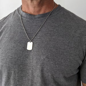 May include: A silver chain necklace with a plain silver rectangular dog tag pendant.