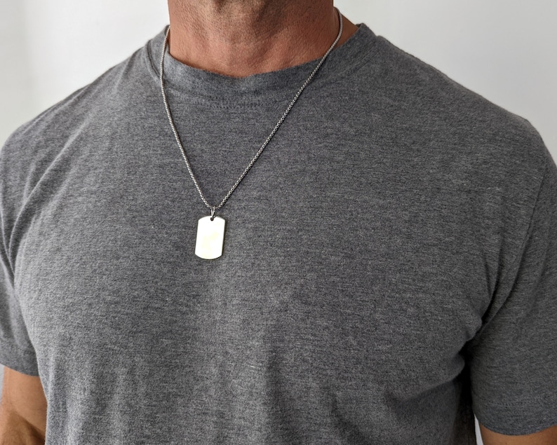 May include: A silver chain necklace with a plain silver rectangular dog tag pendant.