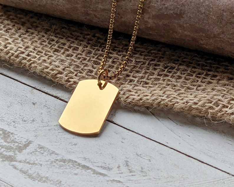 May include: A gold chain necklace with a plain gold rectangular tag pendant.