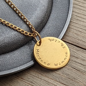 May include: Gold necklace with a round pendant engraved with the words "Winnie", "Morocco", and "Sweet 21".