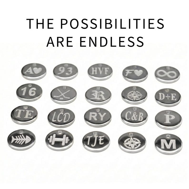 Puede incluir: Una colecci&oacute;n de peque&ntilde;os colgantes grabados de color plateado con varios s&iacute;mbolos y letras. El texto "THE POSSIBILITIES ARE ENDLESS" se muestra encima de los colgantes. Los colgantes incluyen un coraz&oacute;n, un s&iacute;mbolo de infinito y una br&uacute;jula.