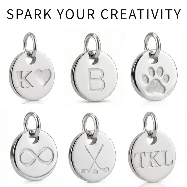 Puede incluir: Colgantes redondos plateados con varios dise&ntilde;os grabados. Uno muestra la letra "K" con un coraz&oacute;n, otro la letra "B", y un tercero una huella de pata. La imagen tambi&eacute;n incluye colgantes con un s&iacute;mbolo de infinito, palos de hockey y las iniciales "TKL". El texto "SPARK YOUR CREATIVITY" est&aacute; en la parte superior.