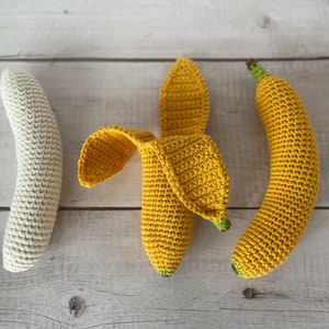 May include: Three crocheted banana toys. One is white, and two are yellow. The yellow bananas are in a curved shape, and the white banana is straight.