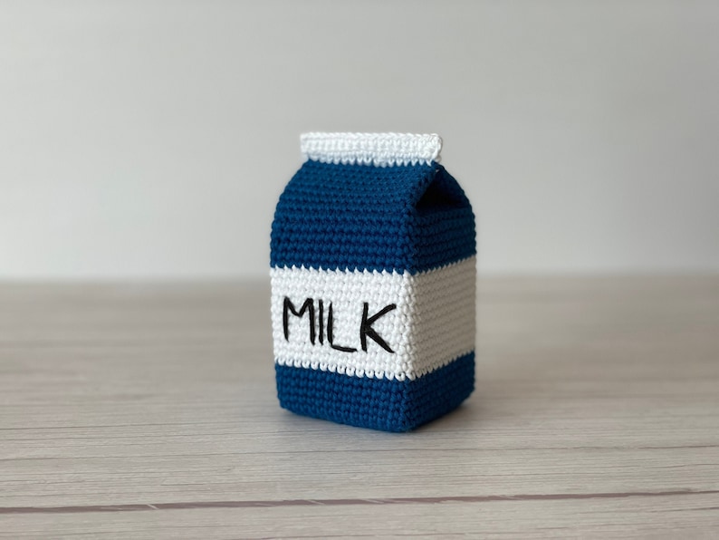 May include: A crocheted milk carton toy, blue and white with the word "MILK" in black lettering.