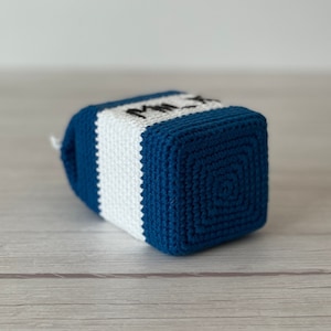 May include: A crocheted milk carton toy in blue and white with the word "Milk" embroidered on the front.