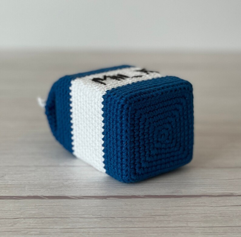 May include: A crocheted milk carton toy in blue and white with the word "Milk" embroidered on the front.
